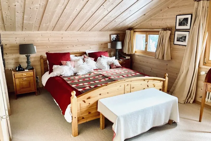 Slaapkamer met houten tweepersoonsbed en rode sprei