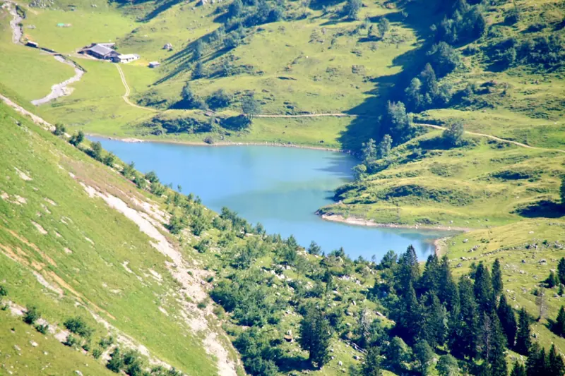 Een bergmeer tussen groene hellingen, van bovenaf gezien