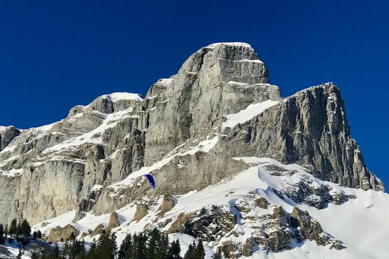 Een paraglider voor een besneeuwde rotswand